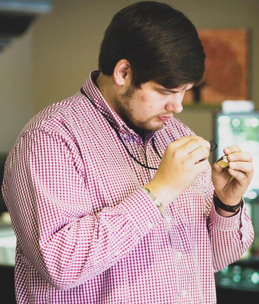 Bill Jewelers accociate looking at a ring with a Loupe